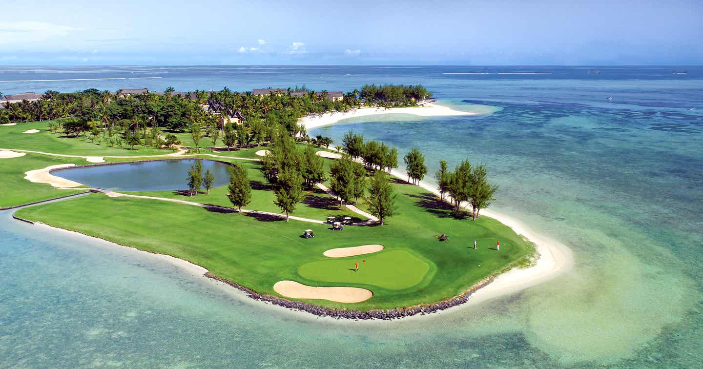 Golfplatz vom Meer umrandet mit Palmen und Sandstücken