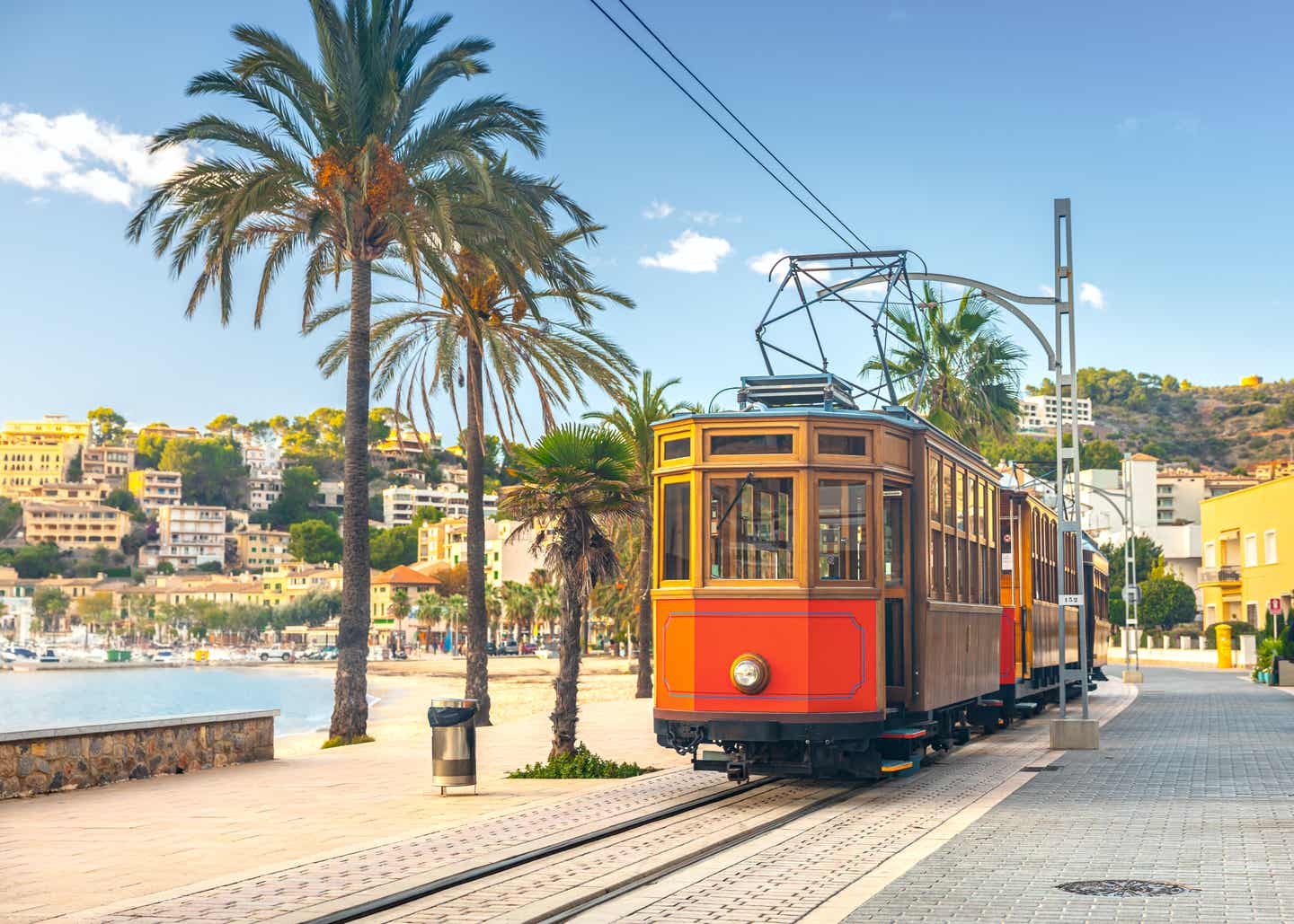 Berühmte orange Straßenbahn von Soller nach Port de Soller auf Mallorca, Spanien – mit Palmen und Küstenblick
