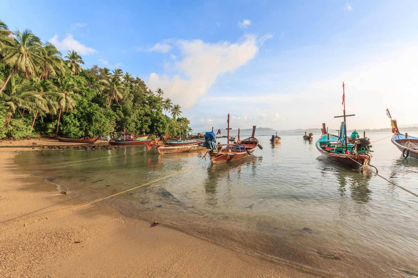 Phukets palmenumsäumter Bang Tao Strand mit Holzbooten