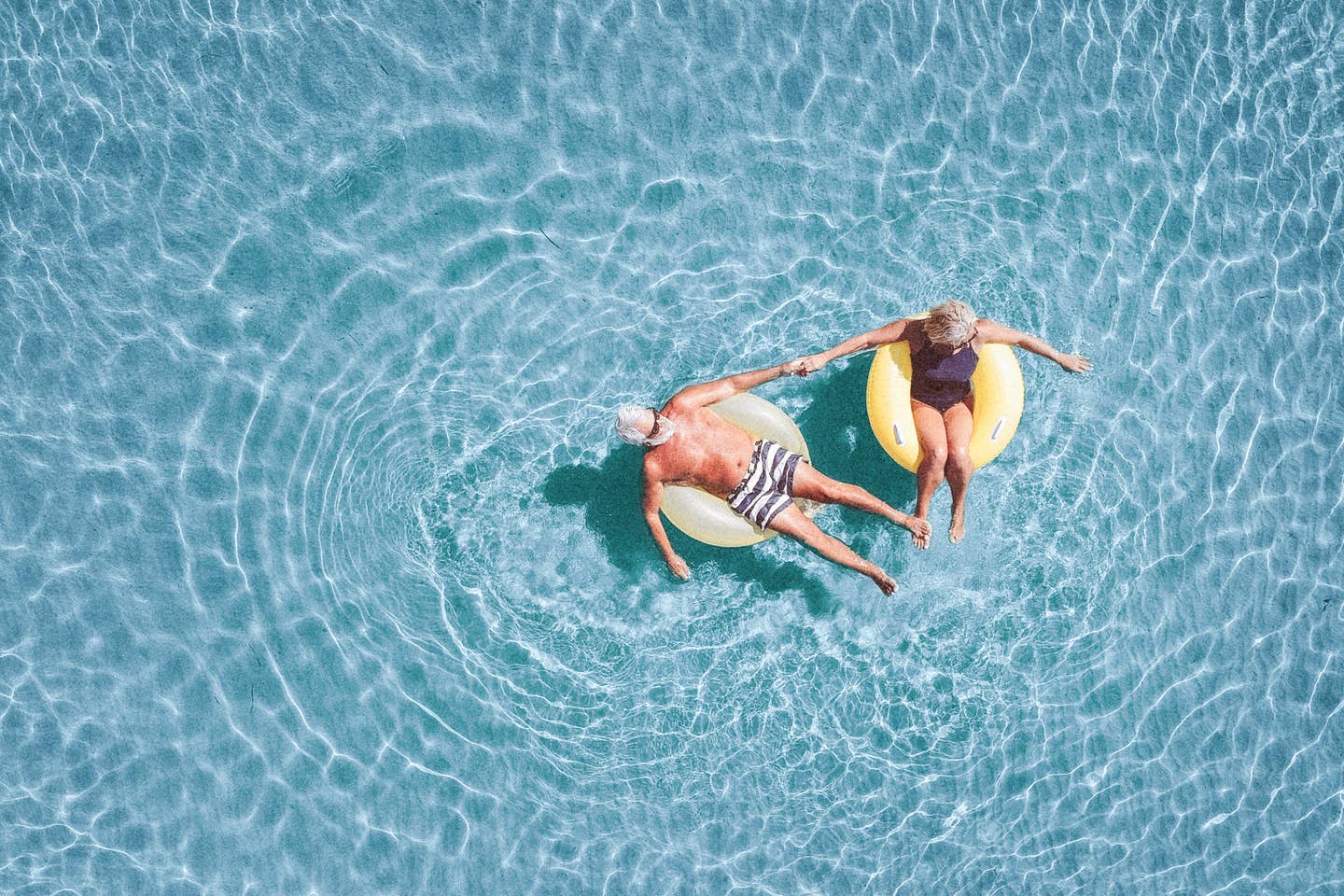 Ein Seniorenpaar schwimmt auf Schwimmreifen im Meer.