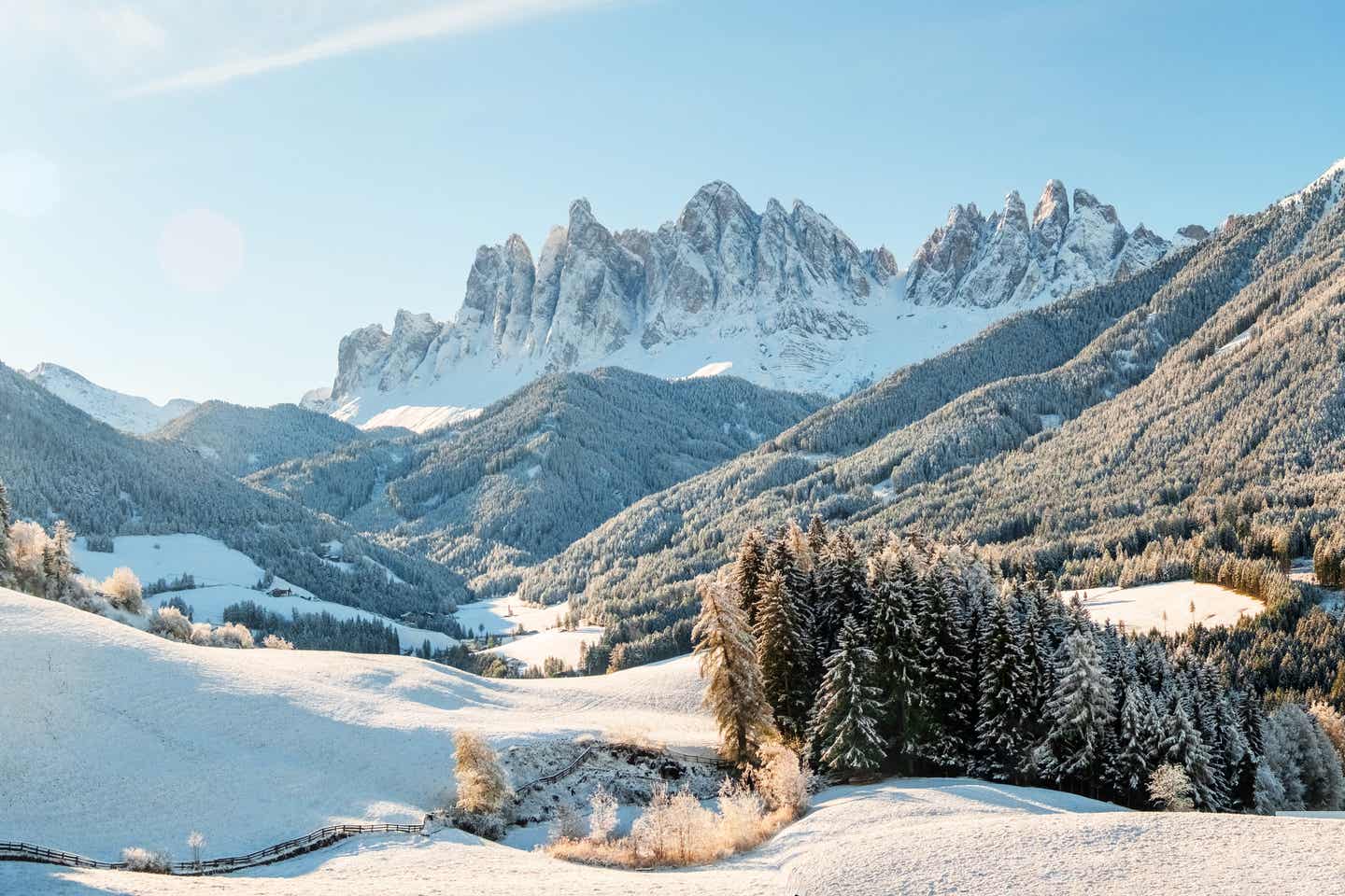 Südtirol Urlaub mit DERTOUR. Verschneites Südtiroler Tal im Sonnenschein mit den Bergen der Geissler-Gruppe im Hintergrund