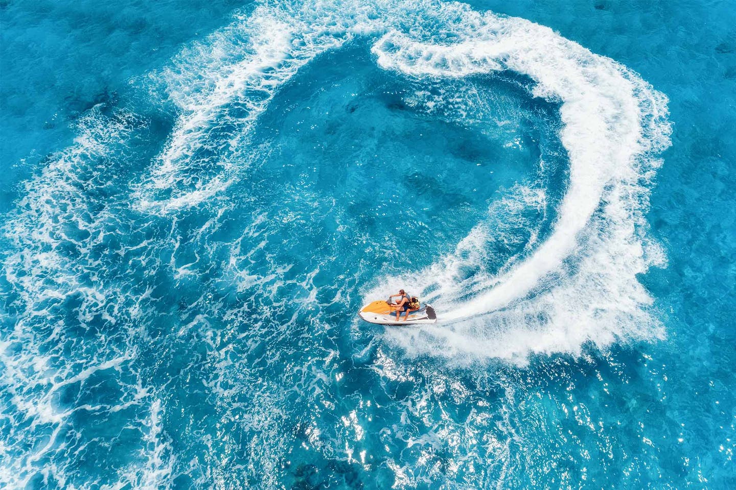 Wassersport beim Inselhopping in Griechenland: Jetskis parken am Strand im Wasser mit sanften Wellen