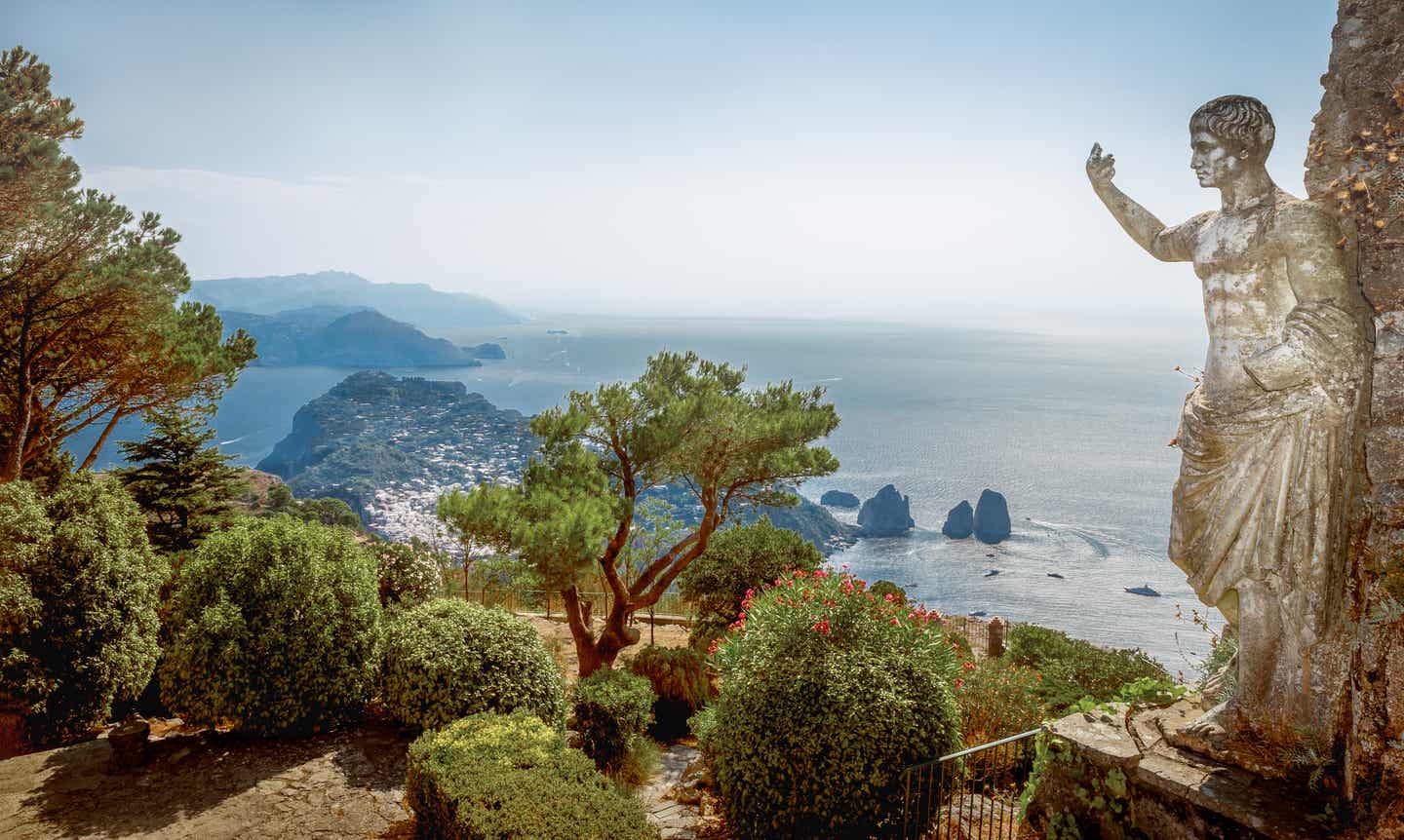 Blick vom Monte Solaro auf Capri; im Vordergrund ein kleiner Park mit einer antiken Statue auf der rechten Seite, im Hintergrund das Meer