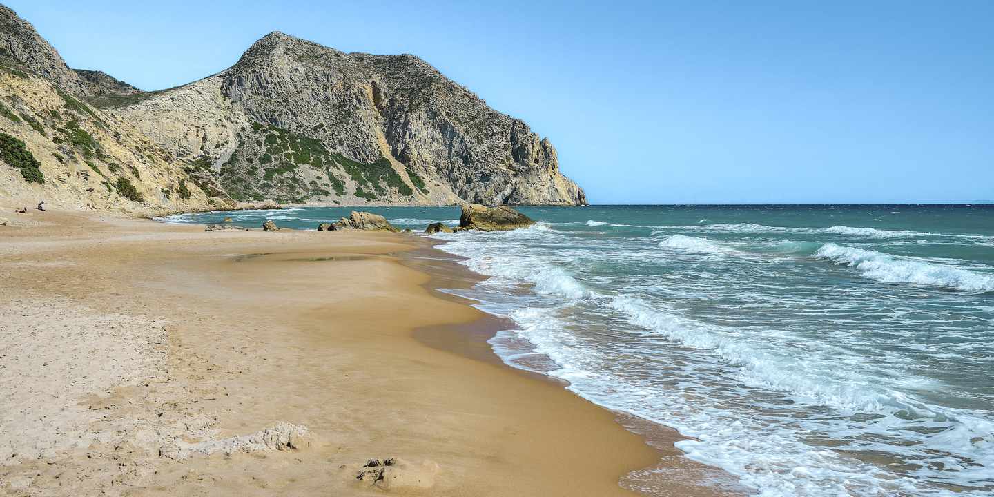 Breiter Sandstrand Kavo Paradiso auf Kos mit türkisfarbenem Meer und felsiger Küstenlandschaft