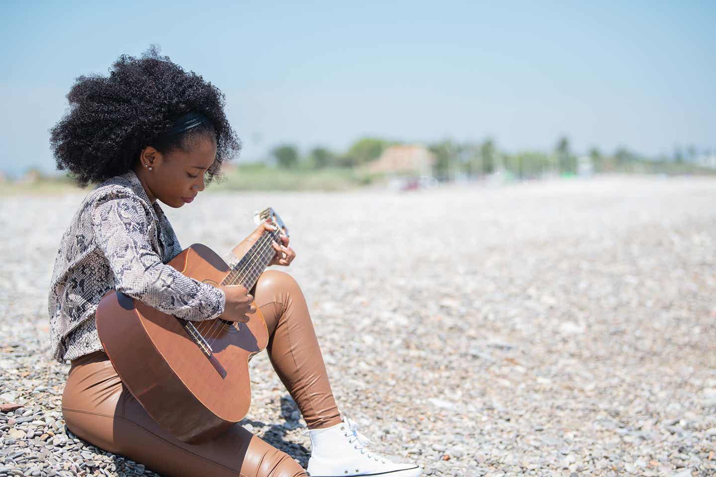 Eine Frau spielt am Strand Gitarre