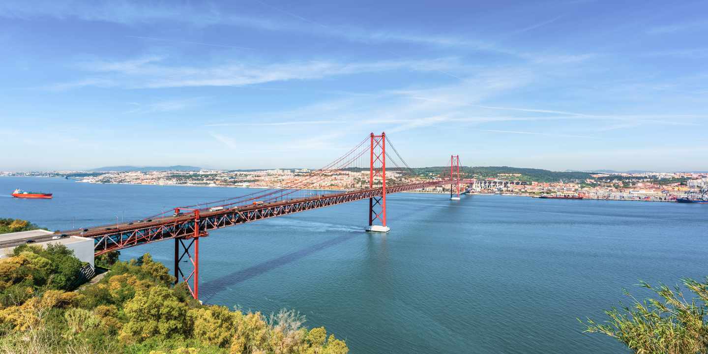 Ponte 25 de Abril über den Tejo mit roter Stahlkonstruktion und Skyline von Lissabon
