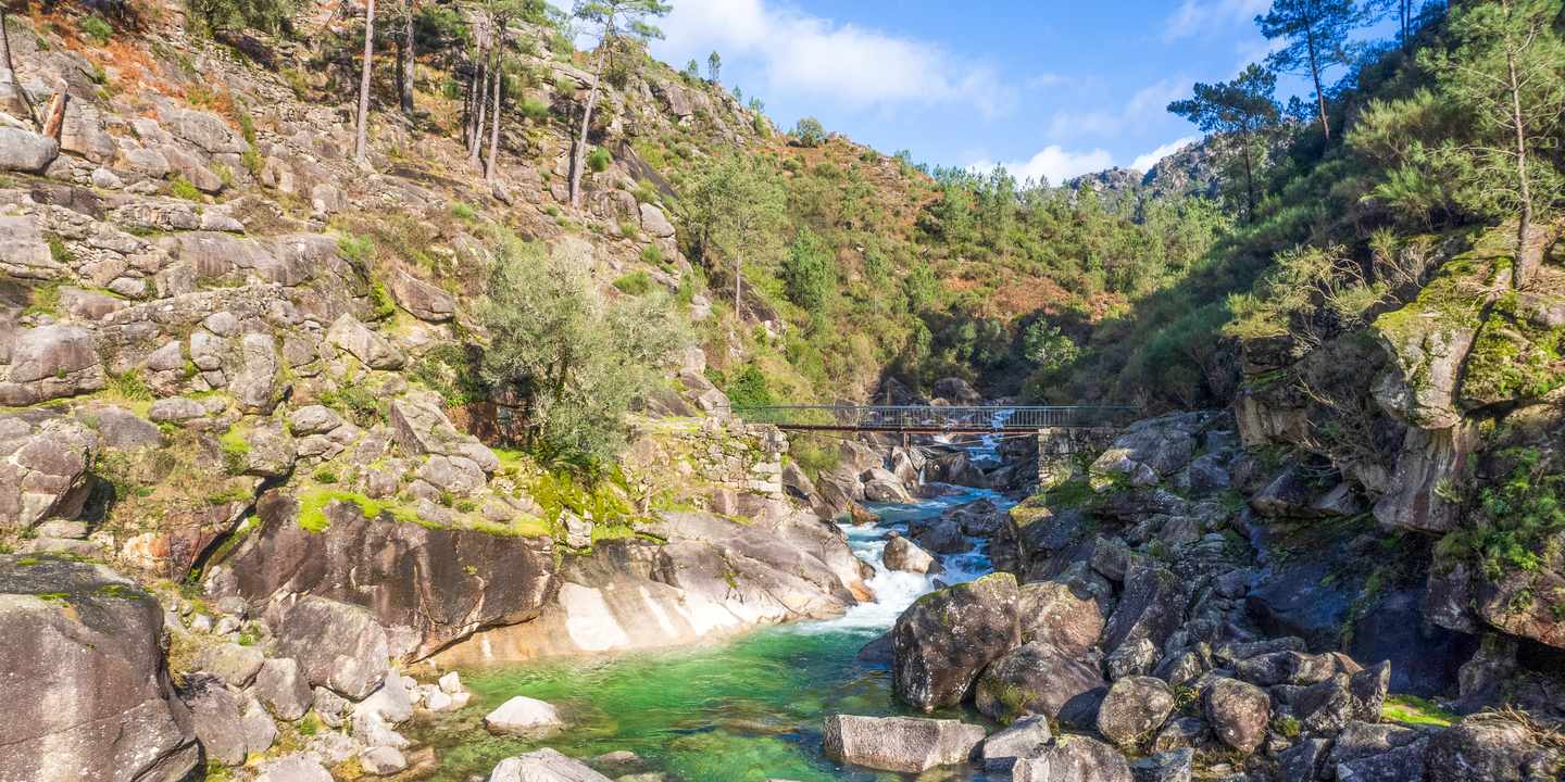 Flusslauf im Nationalpark Peneda-Gerês mit Felsen, klarem Wasser und kleiner Brücke