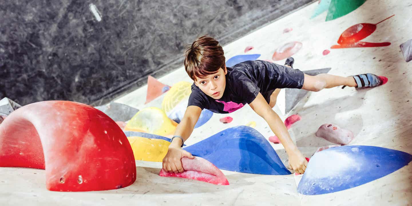 Blick von oben auf einen Jungen, der eine Boulderwand erklimmt