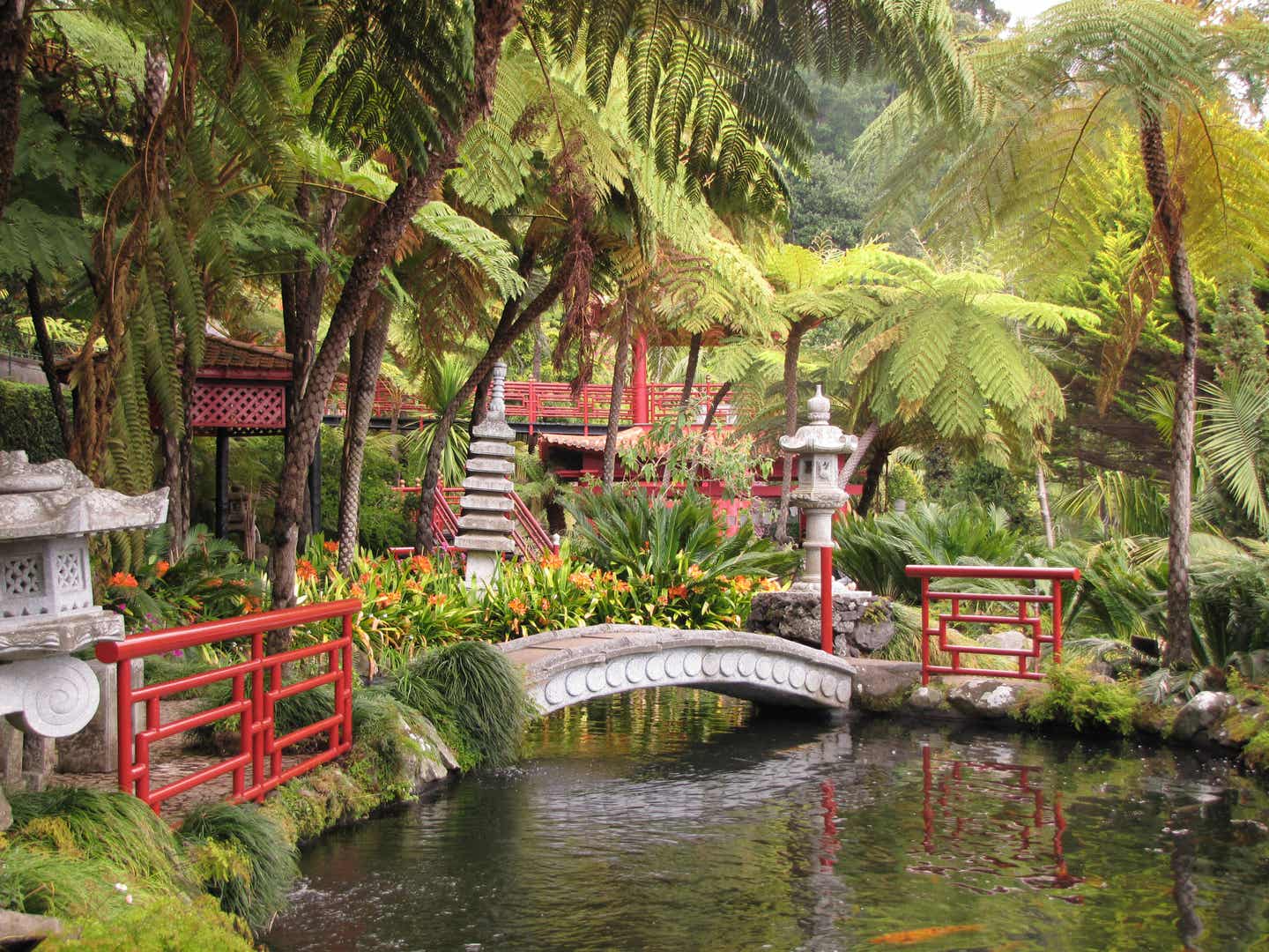 Blick auf rote Pavillons im chinesischen Stil und eine Brücke über einen Teich mit Koi-Karpfen 