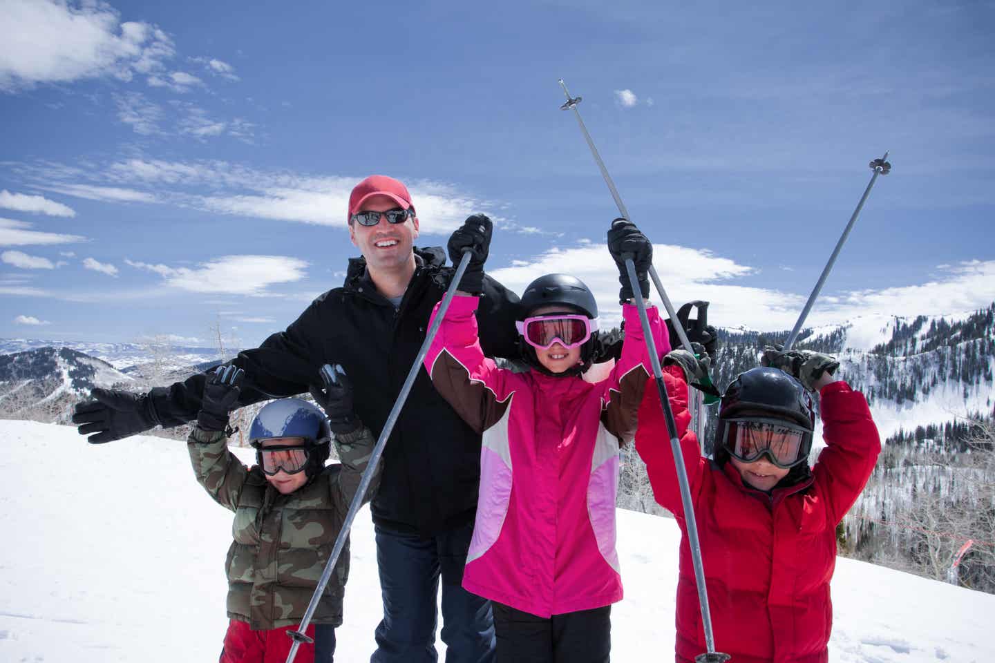 Fröhliche Familie streckt beim Skifahren im Utah-Urlaub die Skistöcke in die Höhe