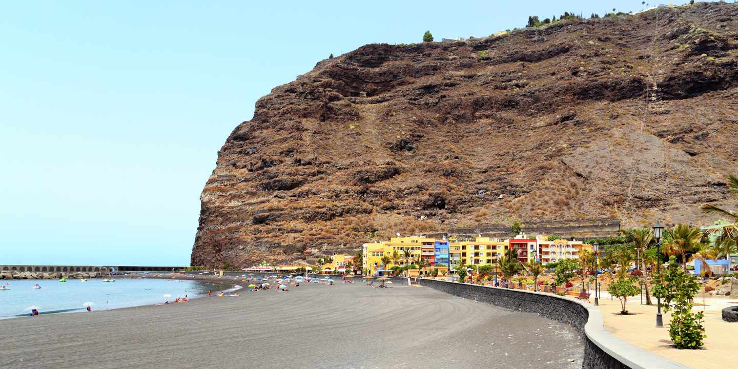 Playa de Tazacorte auf La Palma mit schwarzem Sandstrand, Promenade und steilen Vulkanhängen an der Westküste