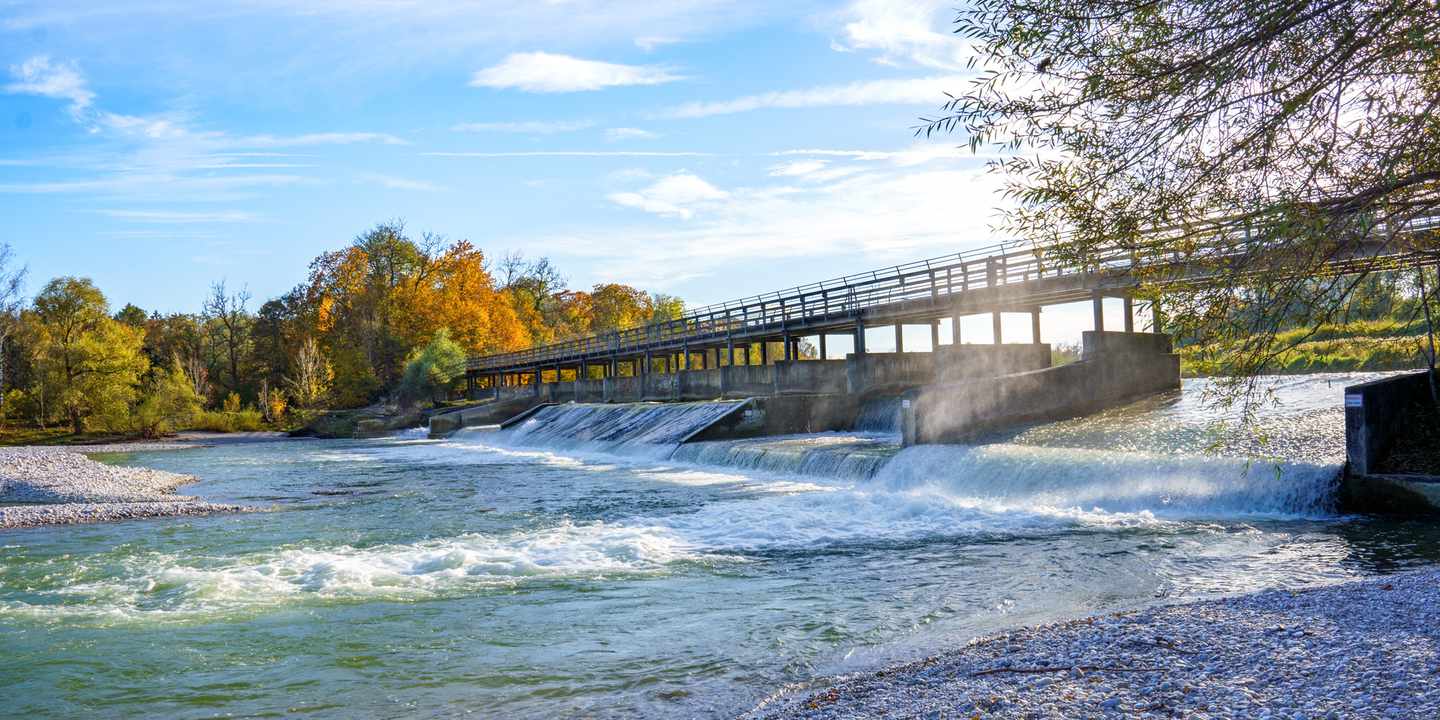 Flauchersteg über die Isar in München mit Radweg und Wehr an einem sonnigen Tag