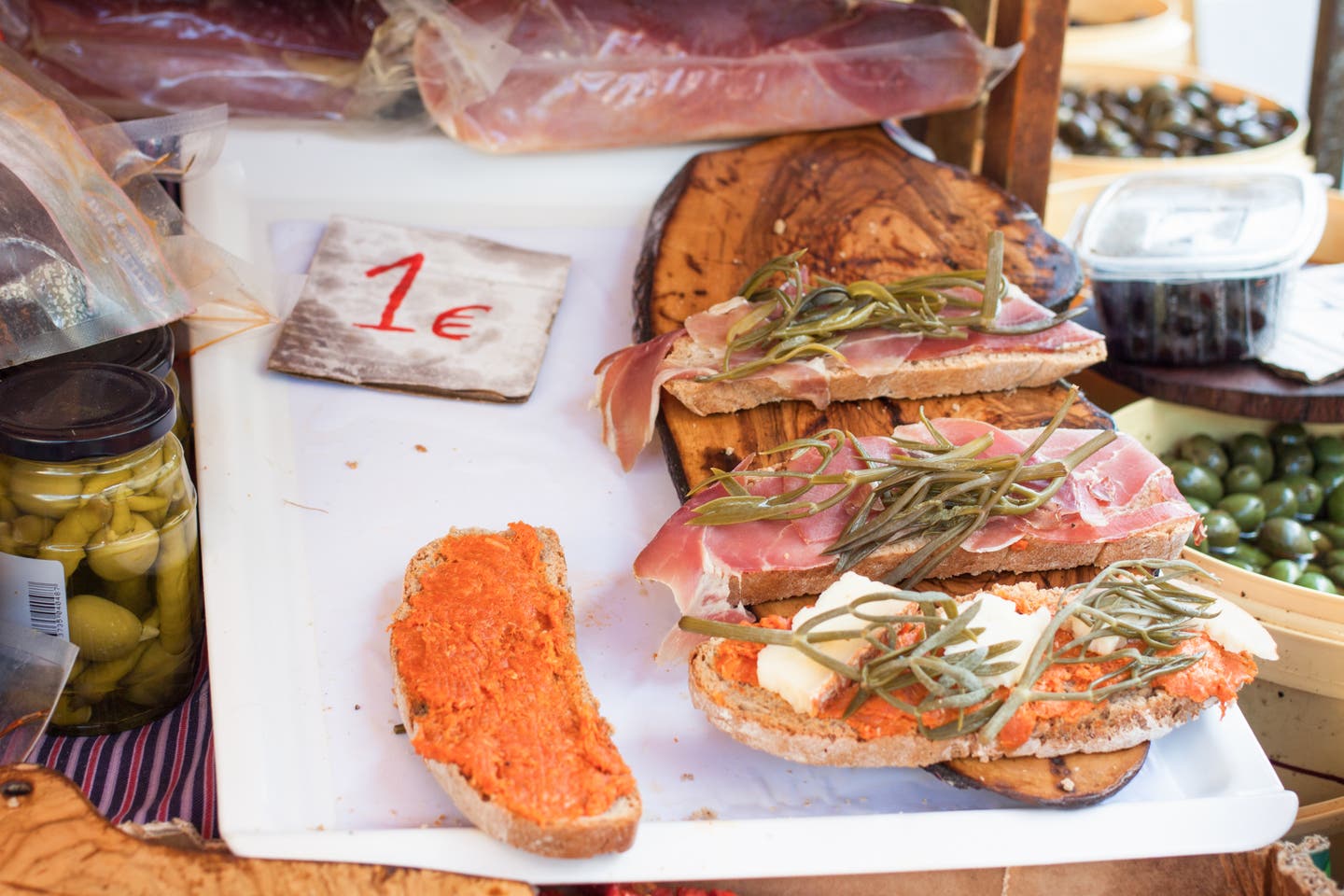 Frisches Pa Amb Oli mit Jamón, Sobrasada und mallorquinischen Kräutern, angeboten auf dem Markt in Sineu, eine traditionelle Mallorca-Spezialität