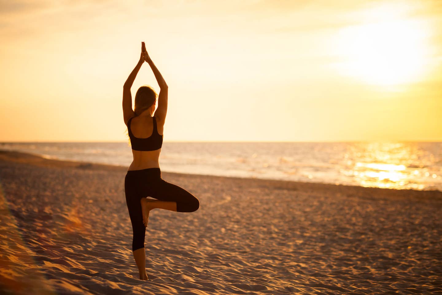 Eine Frau beim Yoga am Strand 