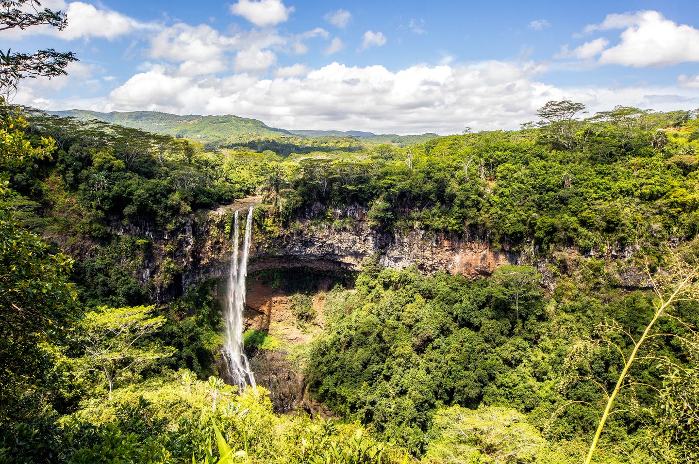 Der Mauritius Wasserfall Chamarel, wie er im Sonnenlicht in die Tiefe stürzt, umgeben von grüner Wildnis.