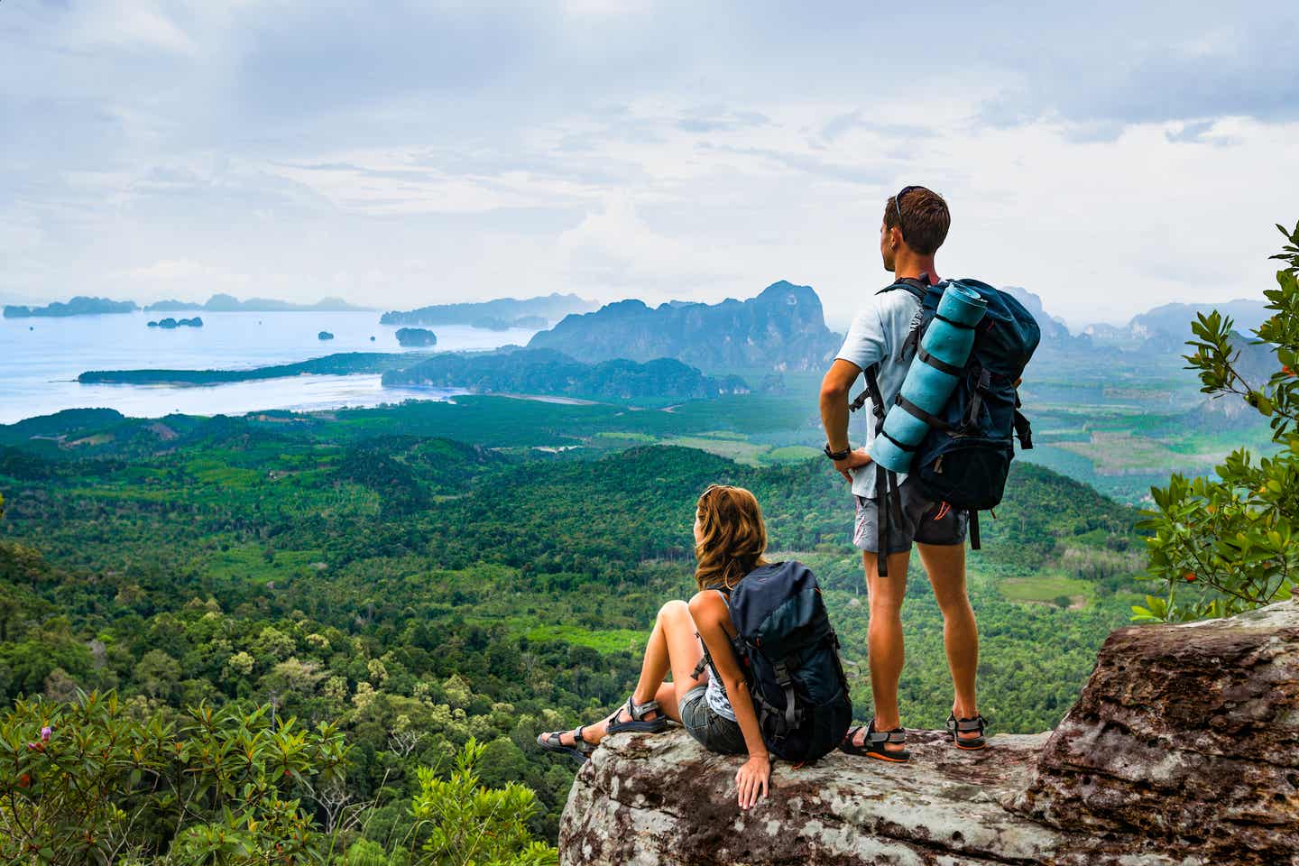 Wanderpaar mit Rucksäcken genießt die Aussicht auf die Berge und Küste