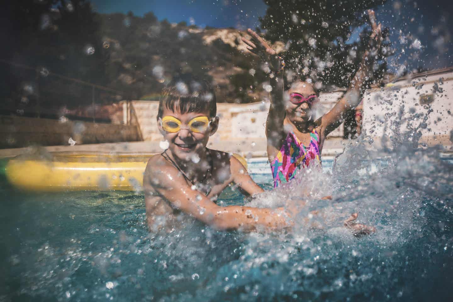 Zypern Urlaub mit DERTOUR. Junge und Mädchen spielen in einem Pool – Wasser spritzt