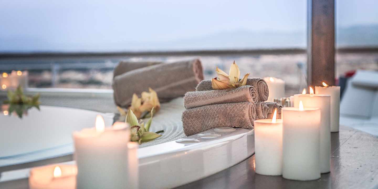 Whirlpool mit Kerzen, Handtüchern und Blüten in einem Wellnesshotel für Paare