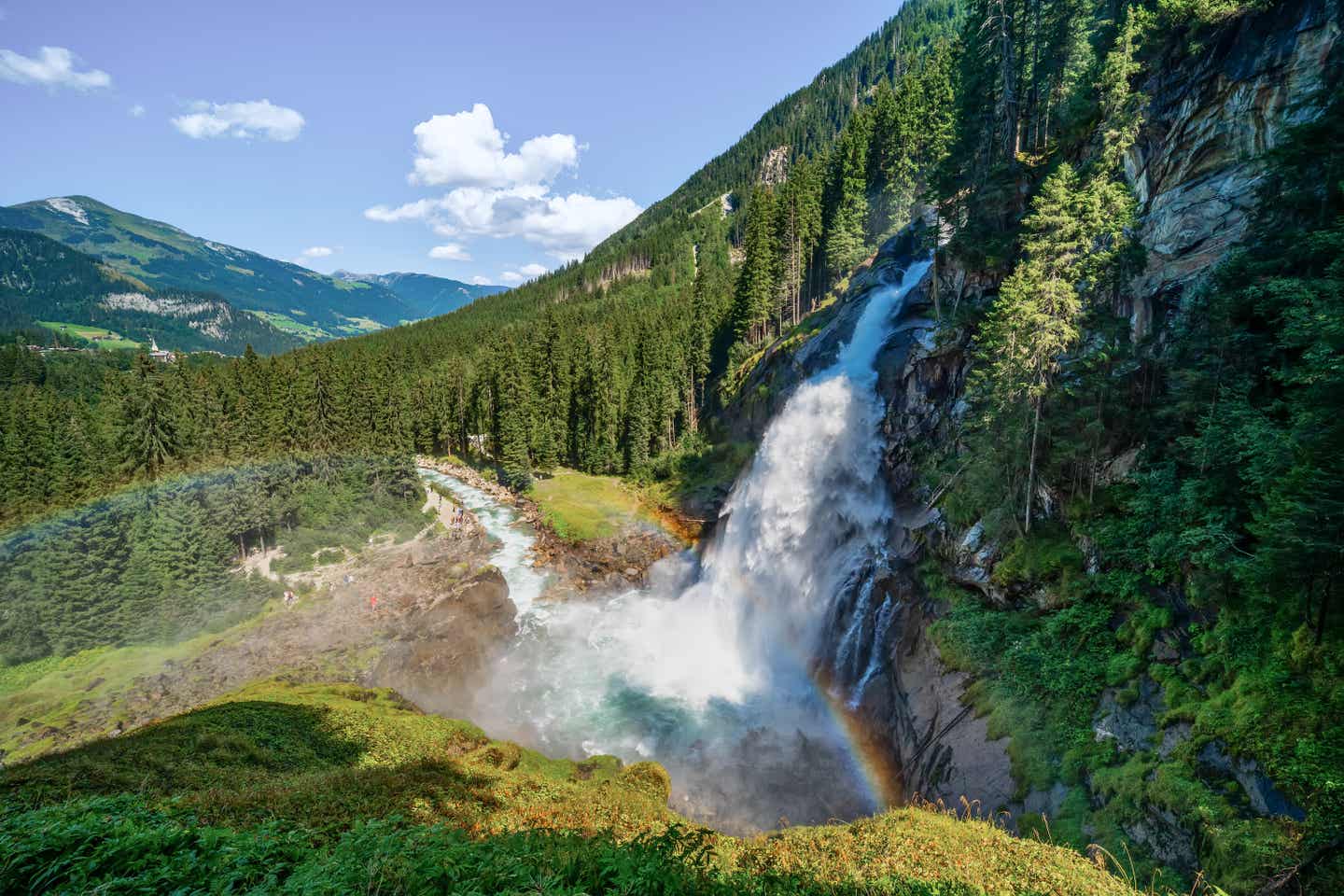 Regenbogen entsteht an einem Wasserfall im grünen Wald