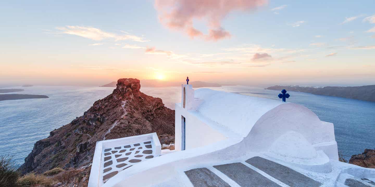 Skaros Rock auf Santorini mit Blick über die Caldera bei Sonnenuntergang und weißer Kapelle im Vordergrund