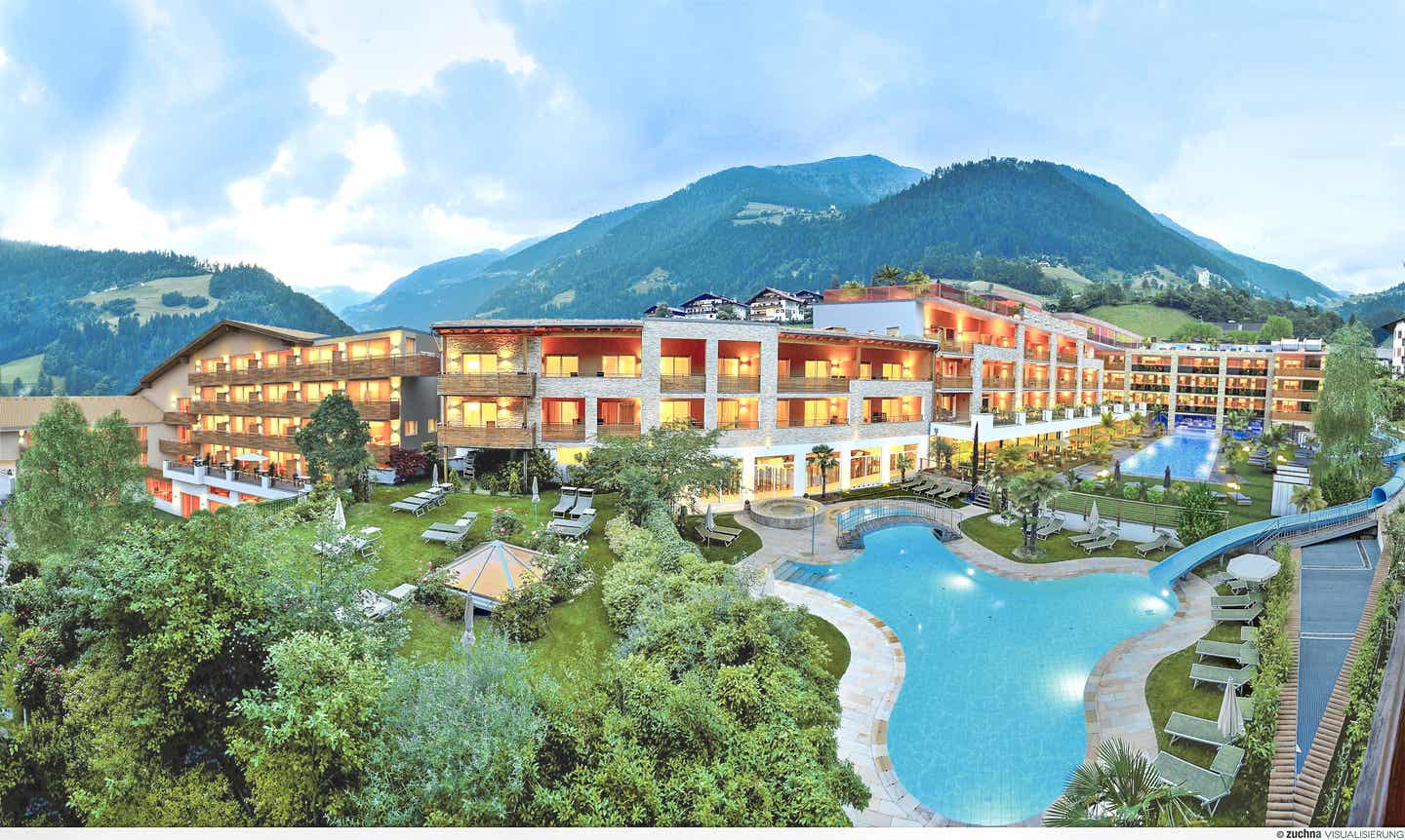 Das stimmungsvoll beleuchtete Stroblhof Active Family Spa Resort von außen, im Hintergrund Berge