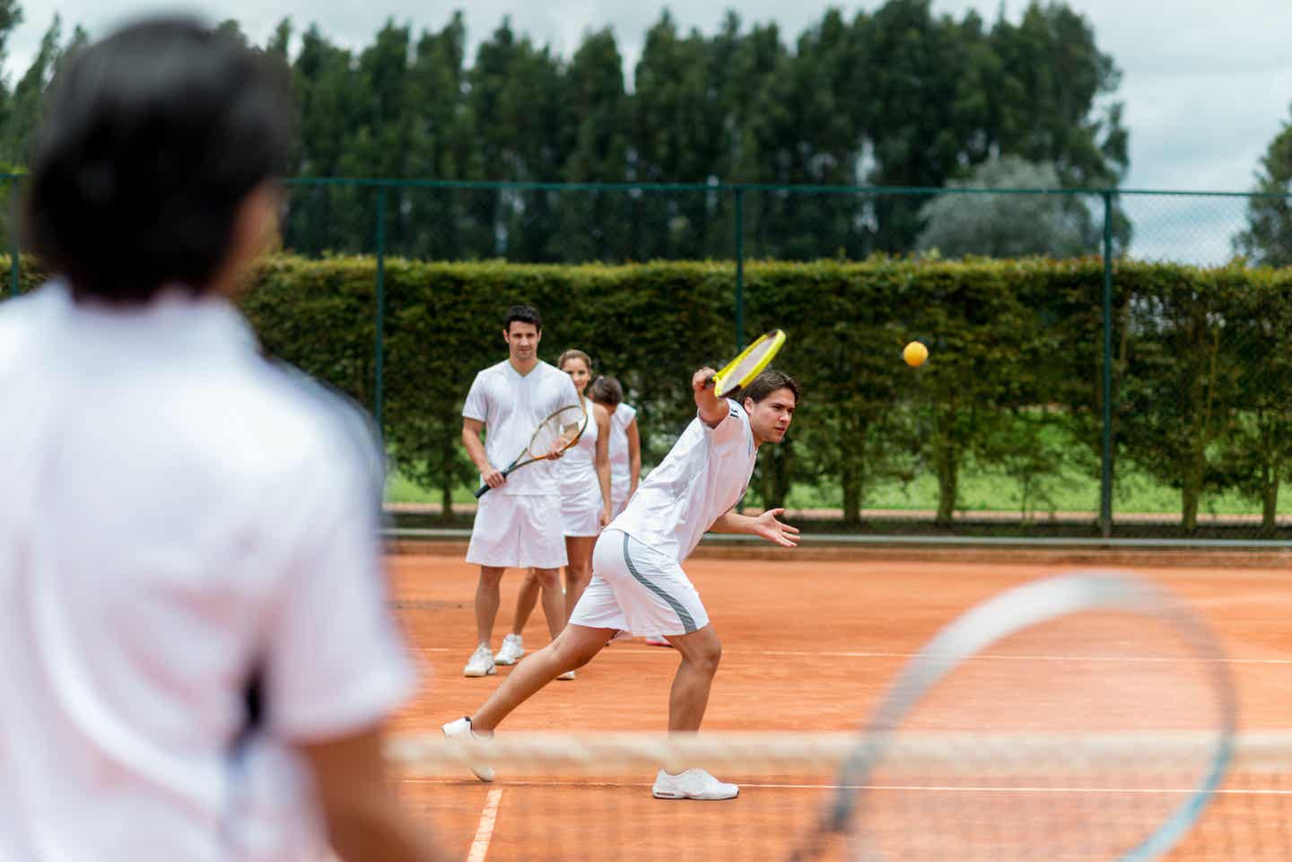 An der Technik zu feilen: Eine Gruppe von Spielern und Spielerinnen nimmt Training beim Tennislehrer.