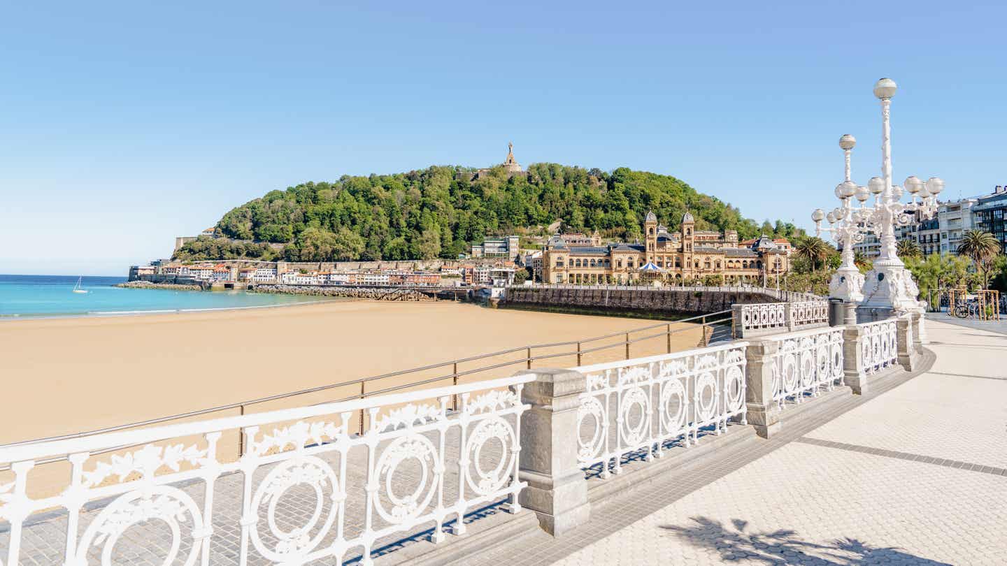 Blick von der Promenade mit schmuckem weißen Zaun auf die Stadt San Sebastián am Strand