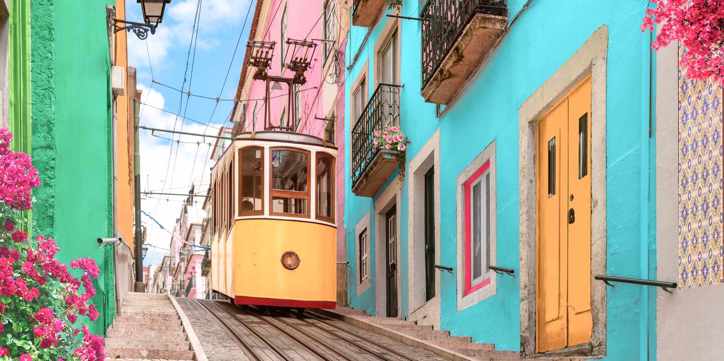 Gelbe Straßenbahn inmitten bunter Häuser in Lissabon