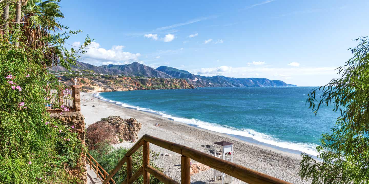 Blick auf eine Bucht mit Meer, Gebirgskette und Sandstrand