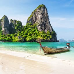 thailand-strandurlaub-traditionelles-boot-ankert-vor-grossen-felsen-im-tuerkisen-wasser-g-1206899165.jpg