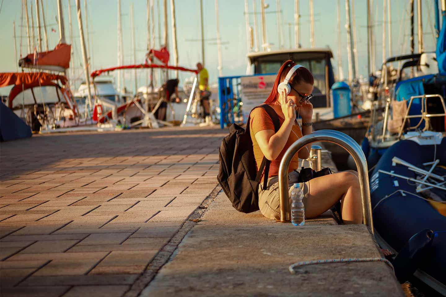 Eine Frau sitzt im Hafen und hört Musik