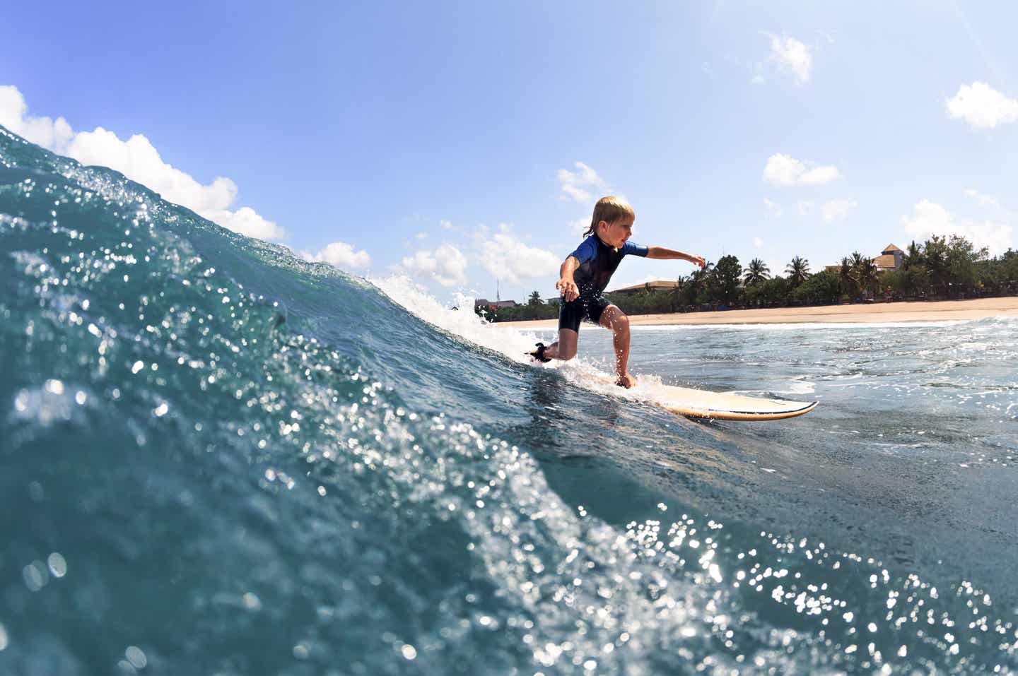 Kleiner Junge surft auf den Wellen