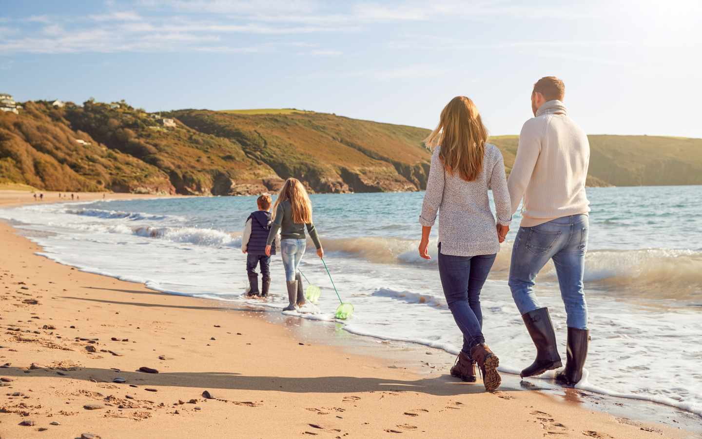 Familie spaziert am Strand im warmen Oktoberlicht beim Herbstferien Urlaub mit Kindern 