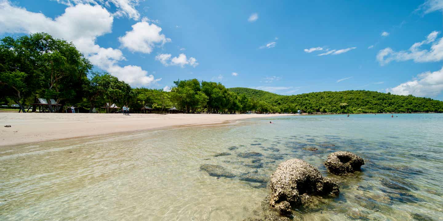 Der Sai Kaew Beach mit klarem Wasser, feinem weißen Sand und schattenspendenden Bäumen im Hintergrund