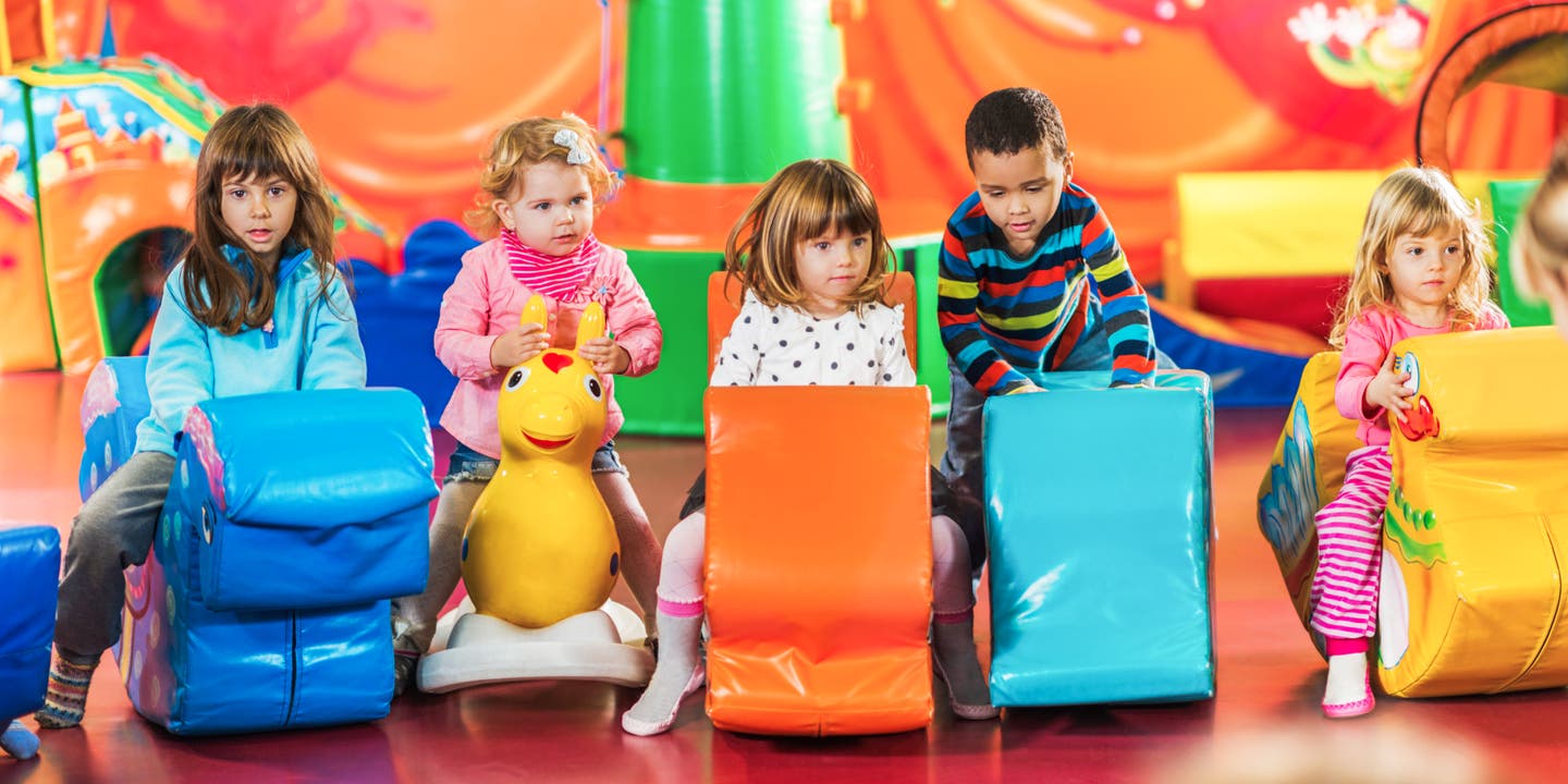 5 Kinder in einem Indoorspielplatz auf Sitztieren