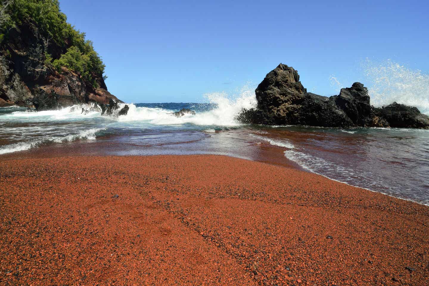 Wellen klatschen auf Felsen am Kaihalulu Beach auf Hawaii und die Gischt spritzt auf vor blauem Himmel