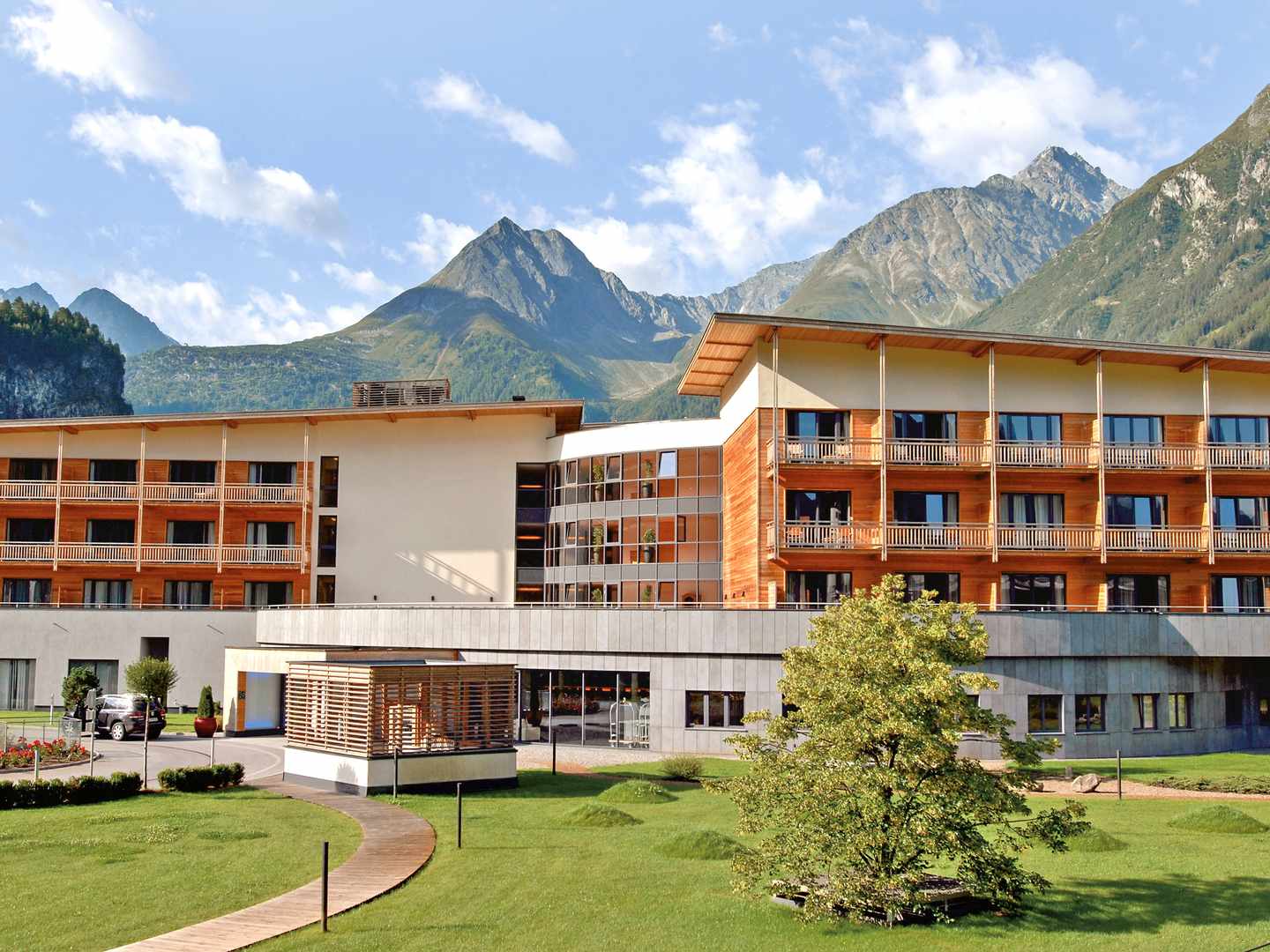 Direkt im Ötztal gelegen: Der Aqua Dome verbindet modernes Design mit Zugang zur alpinen Thermenlandschaft Hotelgebäude des Aqua Dome Längenfeld mit Bergkulisse im Ötztal, Tirol