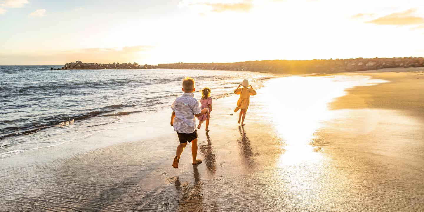 Familienurlaub auf den Kanaren: drei Kinder laufen am Strand umher