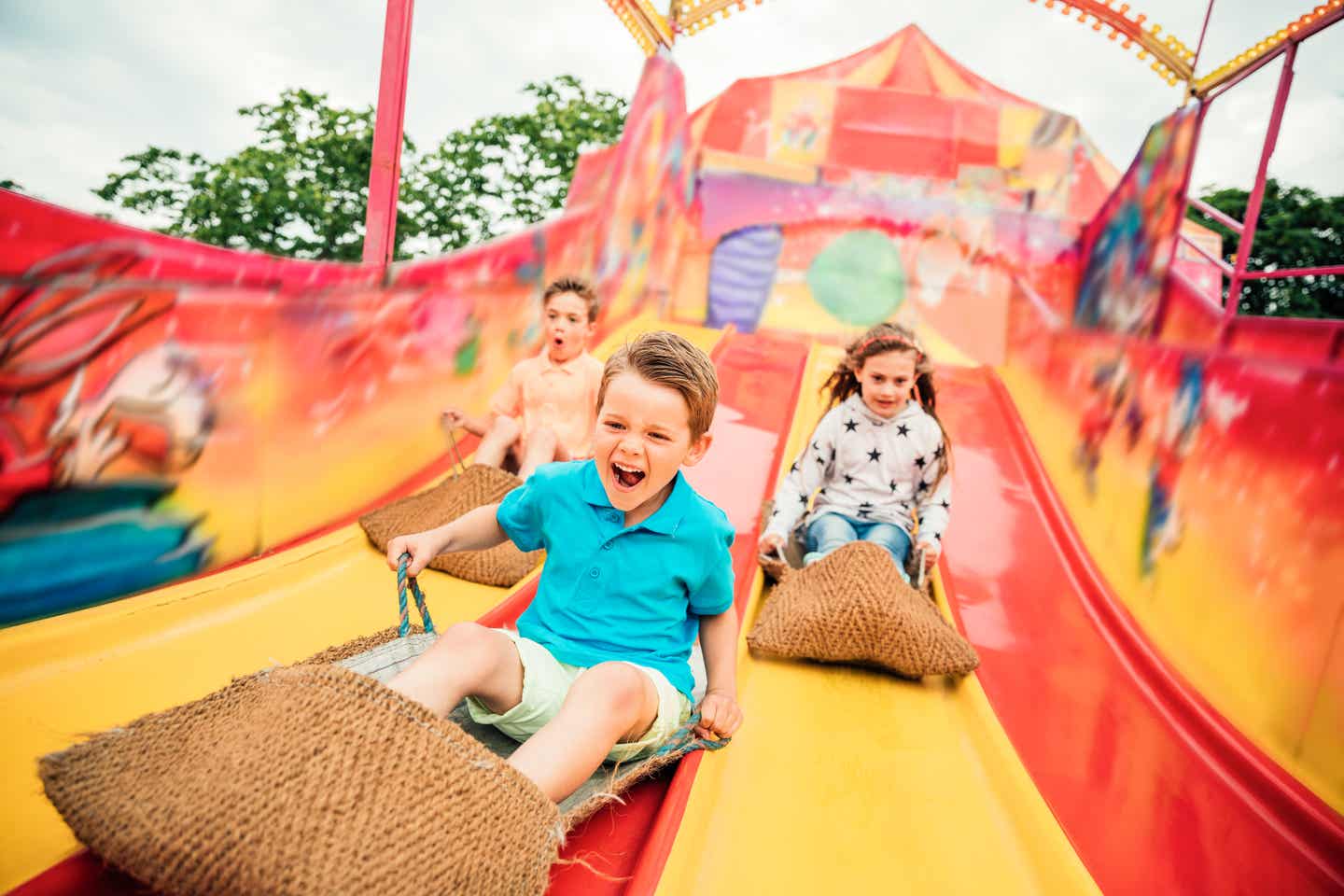 Drei Kinder machen Wettrutschen im Freizeitpark