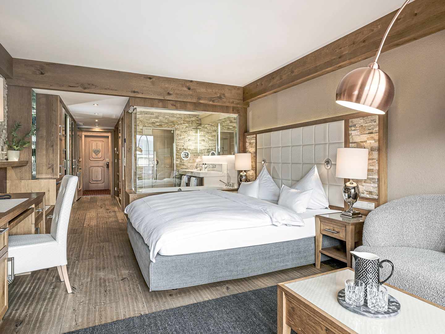 Großzügige Zimmer mit Naturmaterialien und offenem Badkonzept schaffen Ruhe nach dem Spa-Tag Modernes Doppelzimmer mit Holzdesign und offenem Bad im Alpenresort Schwarz in Mieming, Tirol