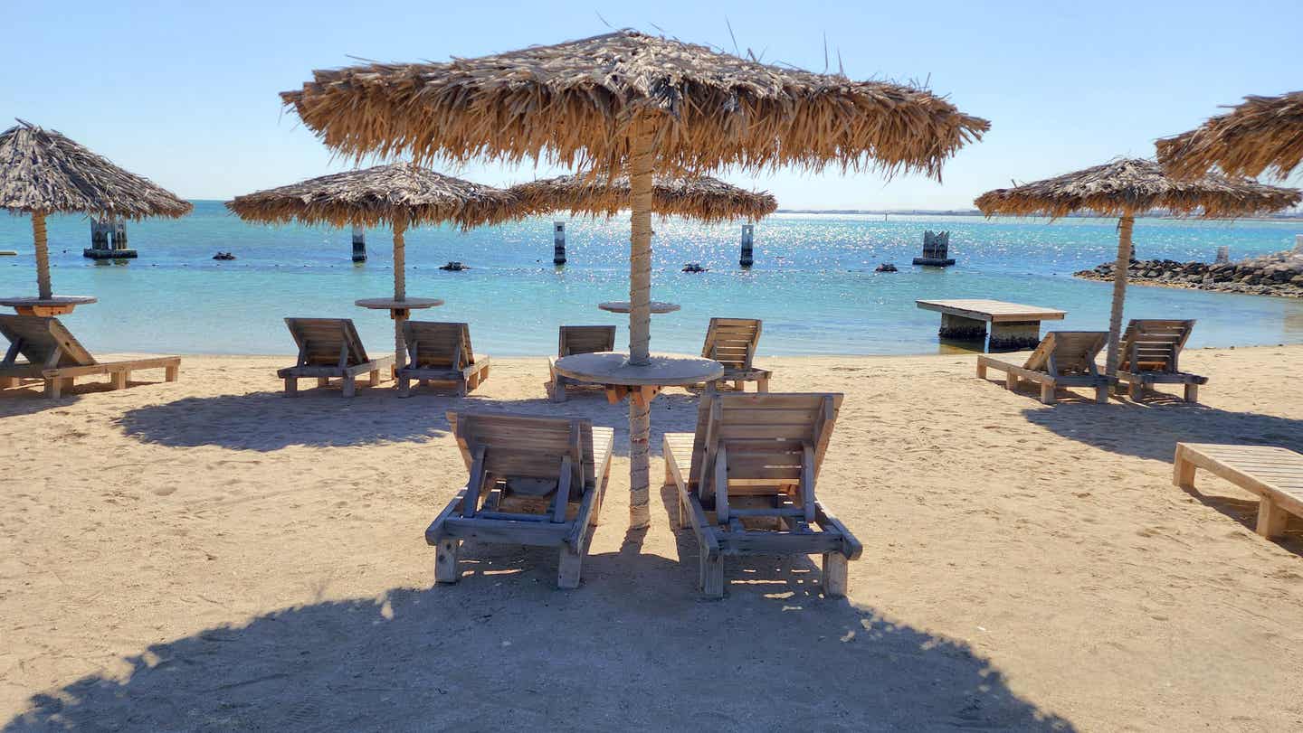 Strand mit Sonnenliegen und Sonnenschirmen auf Aldar Island in Bahrain