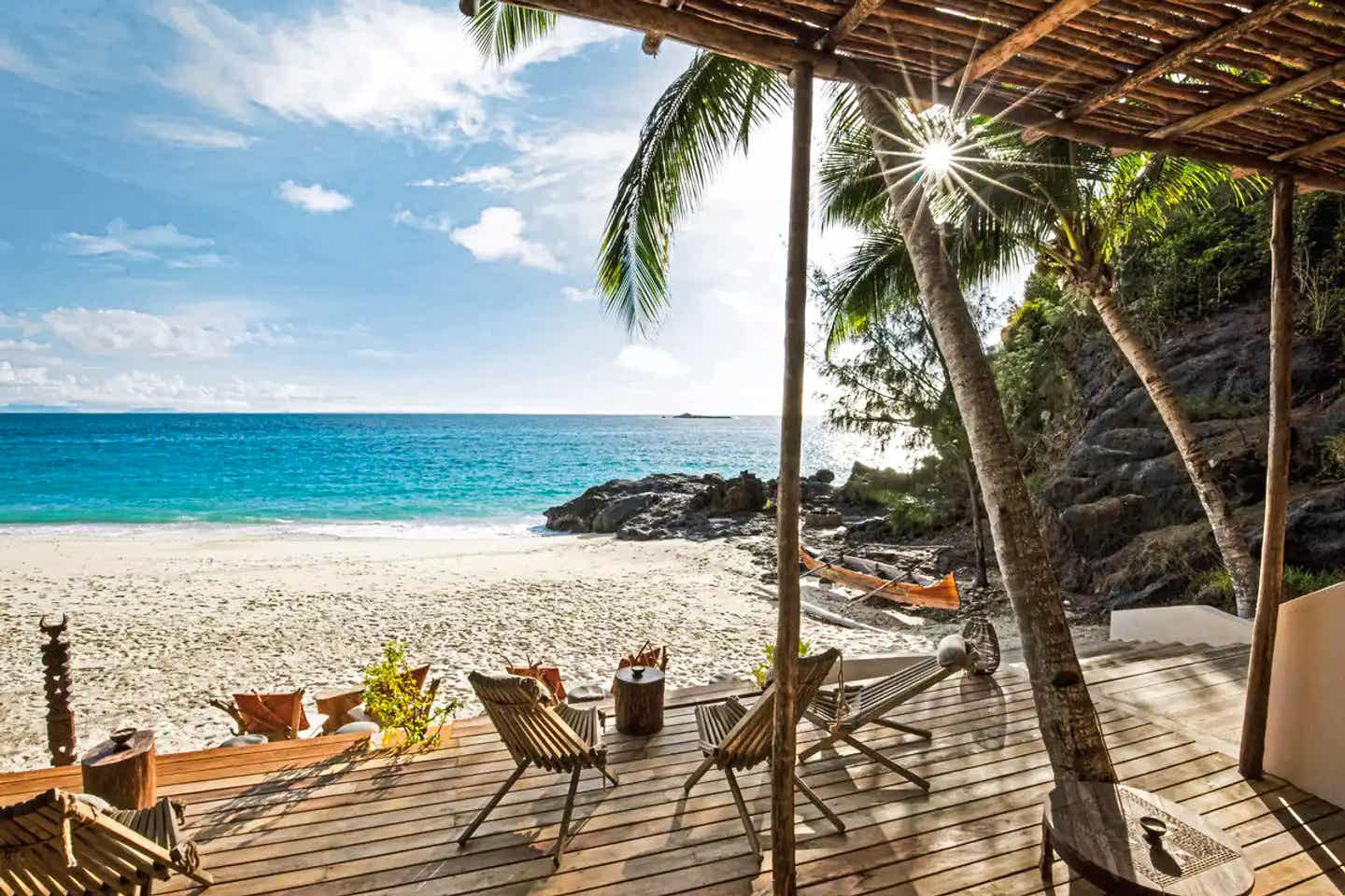 Private Strandterrasse im Constance Tsarabanjina mit Meerblick auf Madagaskar Terrasse eines Bungalows im Constance Tsarabanjina, Madagaskar, mit Holzliegen, Hängematte und direktem Blick auf den Strand der Insel