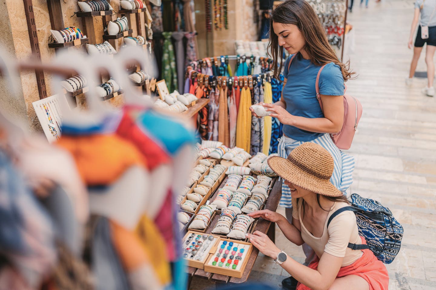 Zwei Frauen stehen an einem Straßenstrand mit Armbändern auf dem Markt von Alcudia