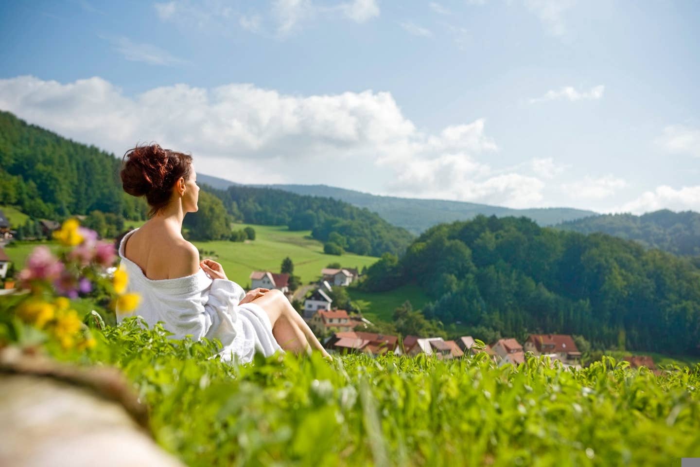 Entspannte Frau auf einer grünen Wiese mit Blick auf die Berge