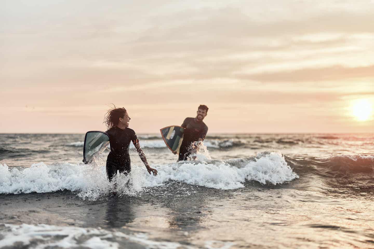 Bali Urlaub: Surferin und Surfer laufen im Meer