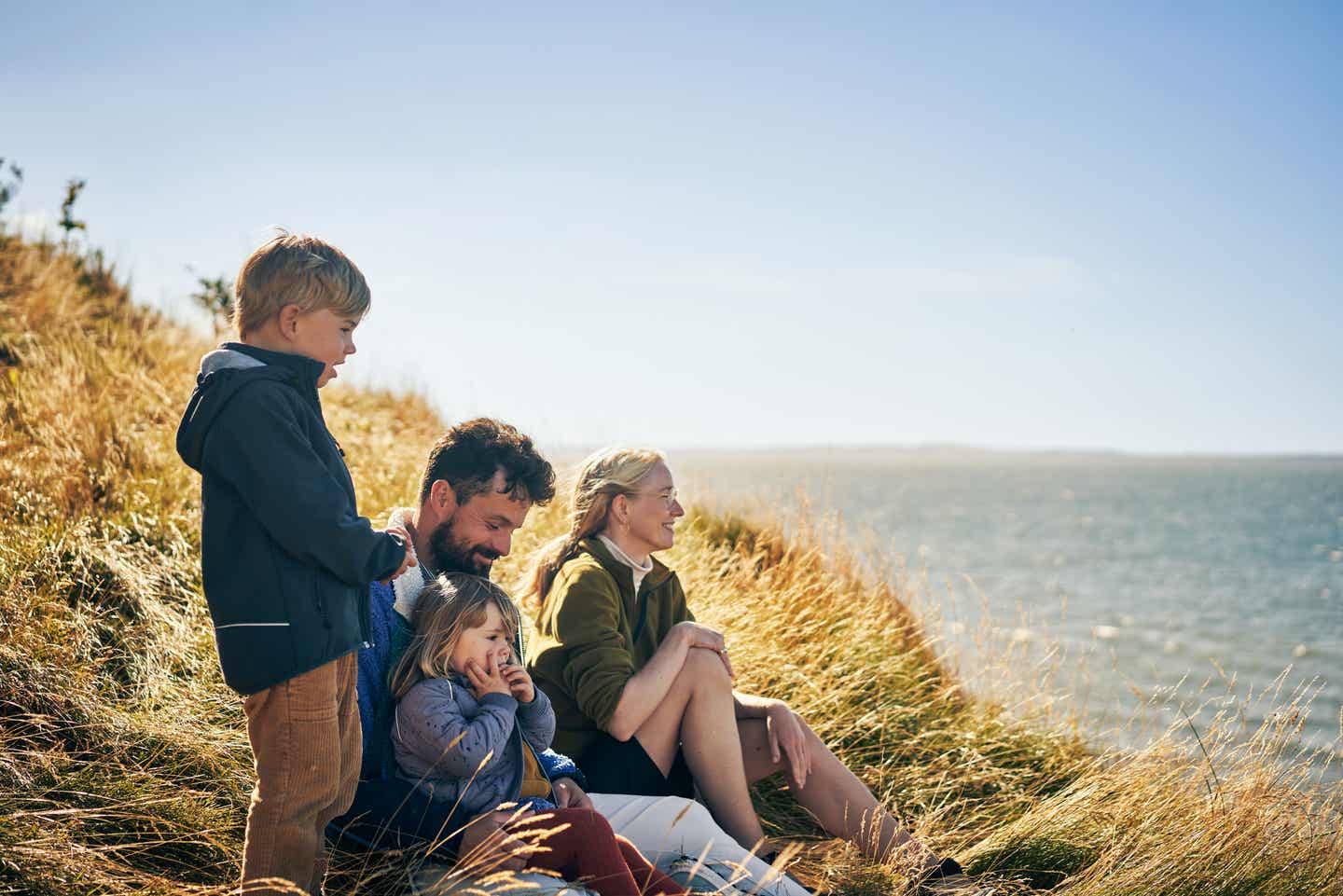 Familie sitzt im Familienurlaub All-Inclusive gemeinsam am Meer