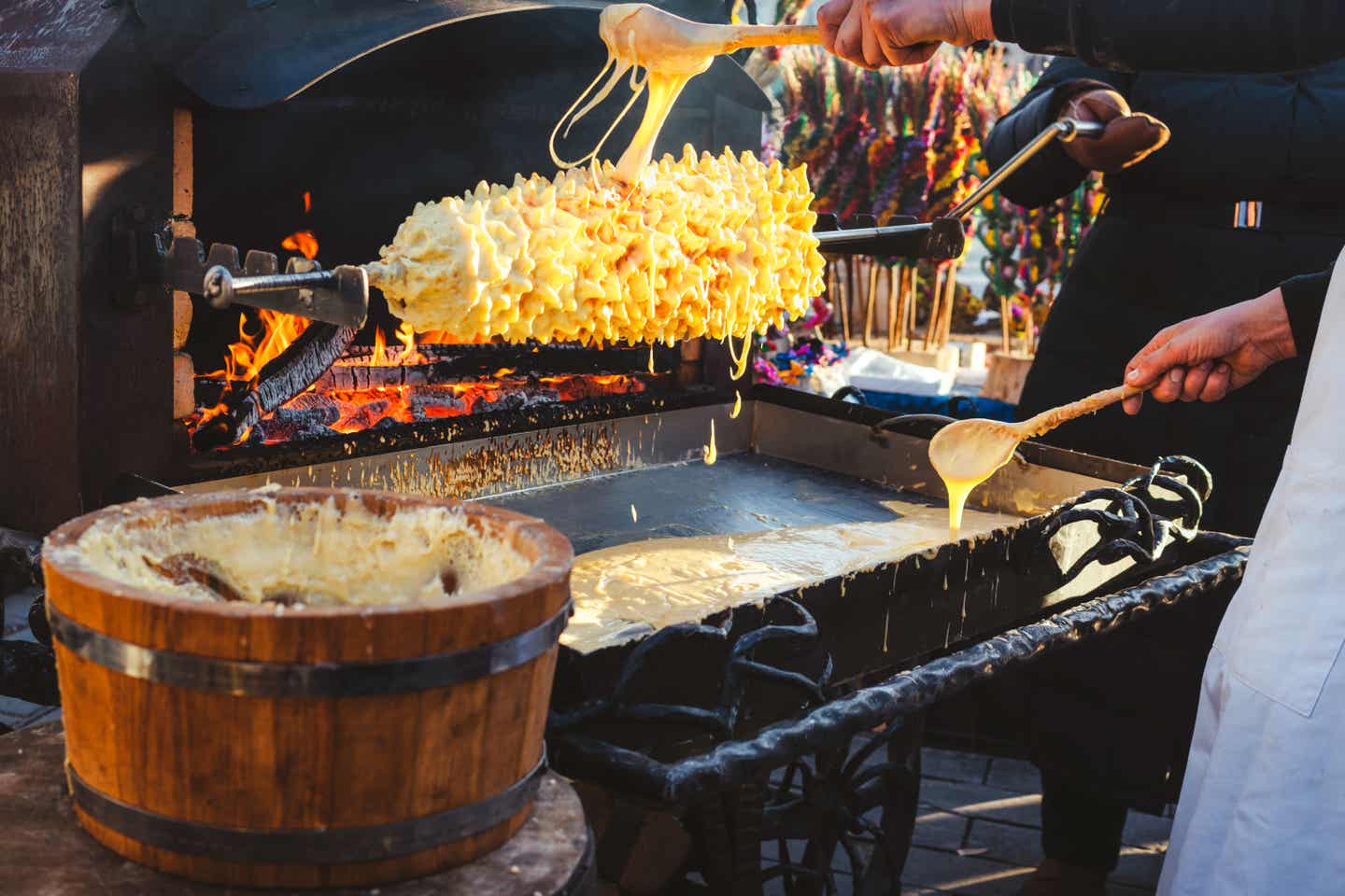 Stand an einem Straßenfest stellt klassischen Baumkuchen aus Teig her Baltisches süßes Streetfood: Baumkuchen handgemacht
