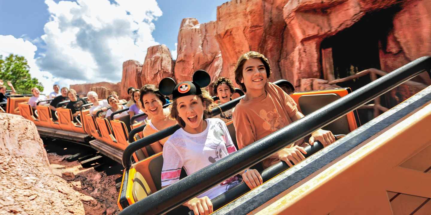 Achterbahn im Disneyland Resort Anaheim mit lachenden Gästen in Themenkulisse aus rotem Fels