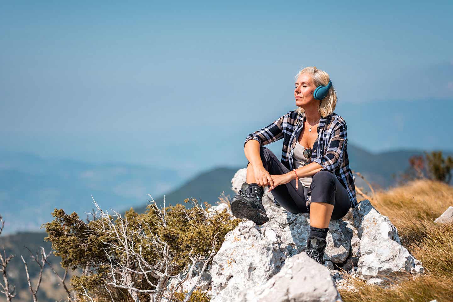 Frau entspannt während einer Wanderpause beim Musikhören