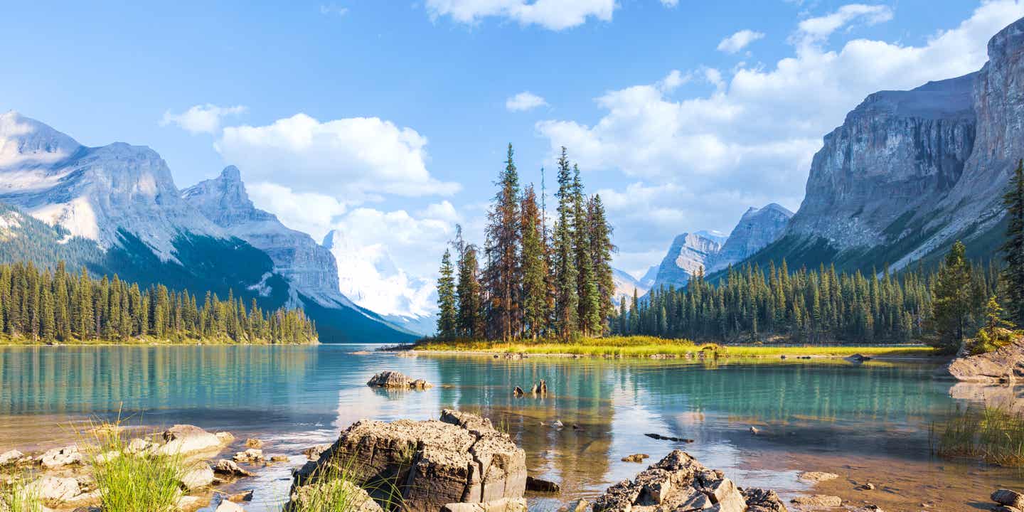Blick auf Spirit Island im türkisblauen Maligne Lake im Jasper Nationalpark, umgeben von Bergen und Wald